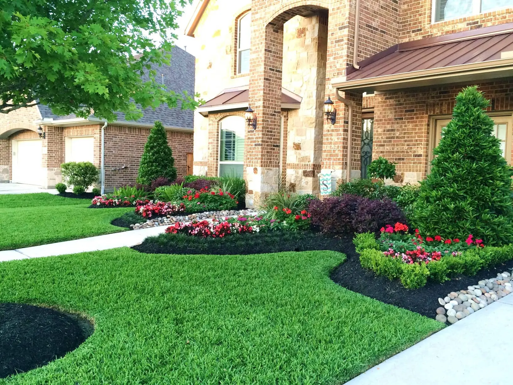 Landscaped front yard with flower beds, shrubs, and green lawn in Katy, TX