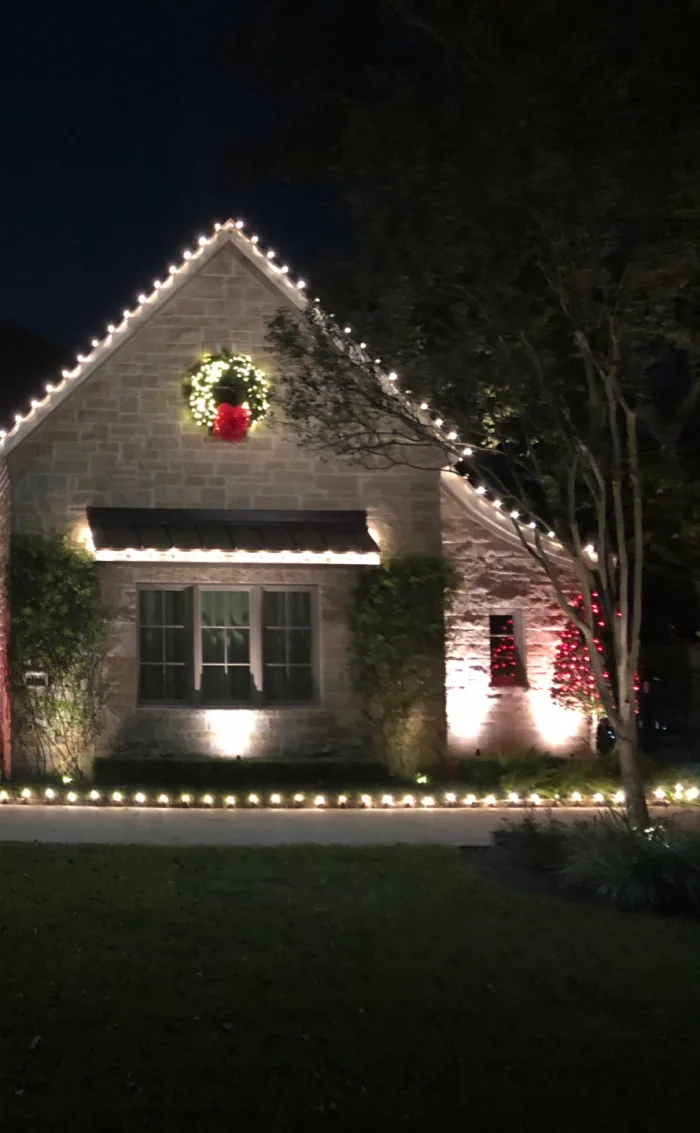 Christmas lights installed on a roofline, wreath and walkway of a Katy home