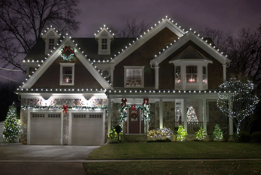 White Christmas lights outlining a home's roofline and garland