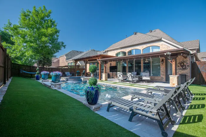 Turf lawn running to the pool deck of a Texas backyard